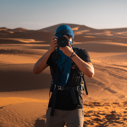 Photographer taking pictures in the sunny merzouga desert during a travel in morocco